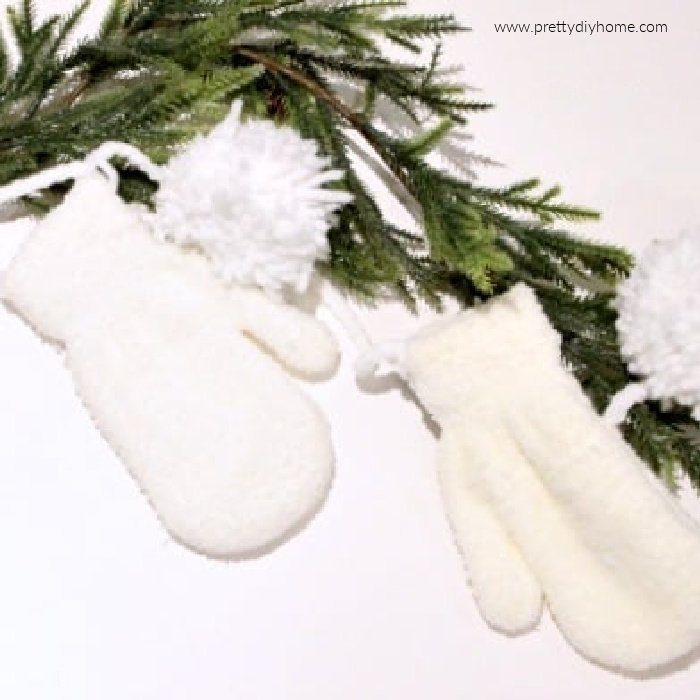 White mittens and pom poms for a DIY Christmas Garland.