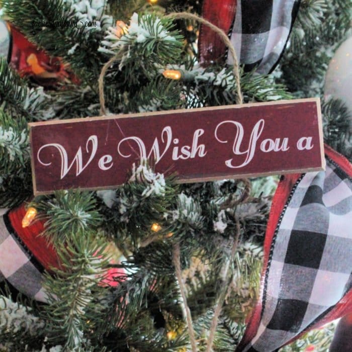 A handmade Christmas ornament hanging on the Christmas tree made of wood with letters.