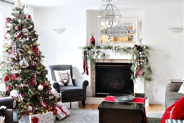 Traditional Christmas decor in a livingroom including a green, red and white mantel, and large traditional Christmas tree.