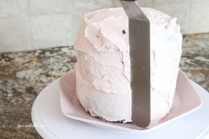 Adding a smooth soft pink cream cheese icing layer to chocolate strawberry valentines cake