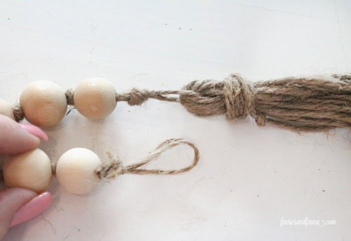 Closing the end loop of a diy farmhouse bead garland with tassels.