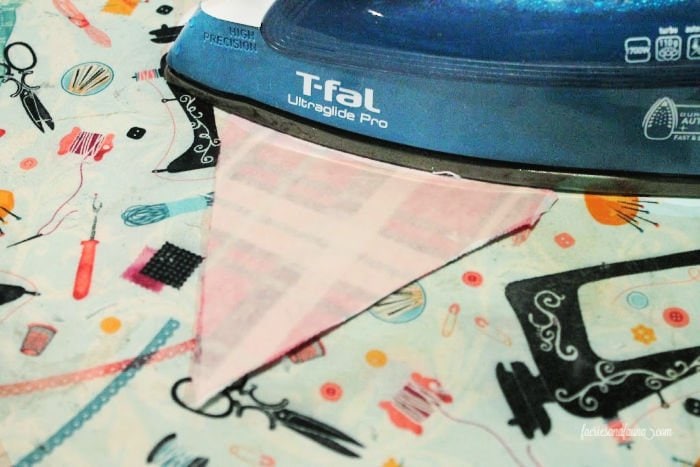 Ironing fabric to create hems on a DIY fabric pennant for a toy box.