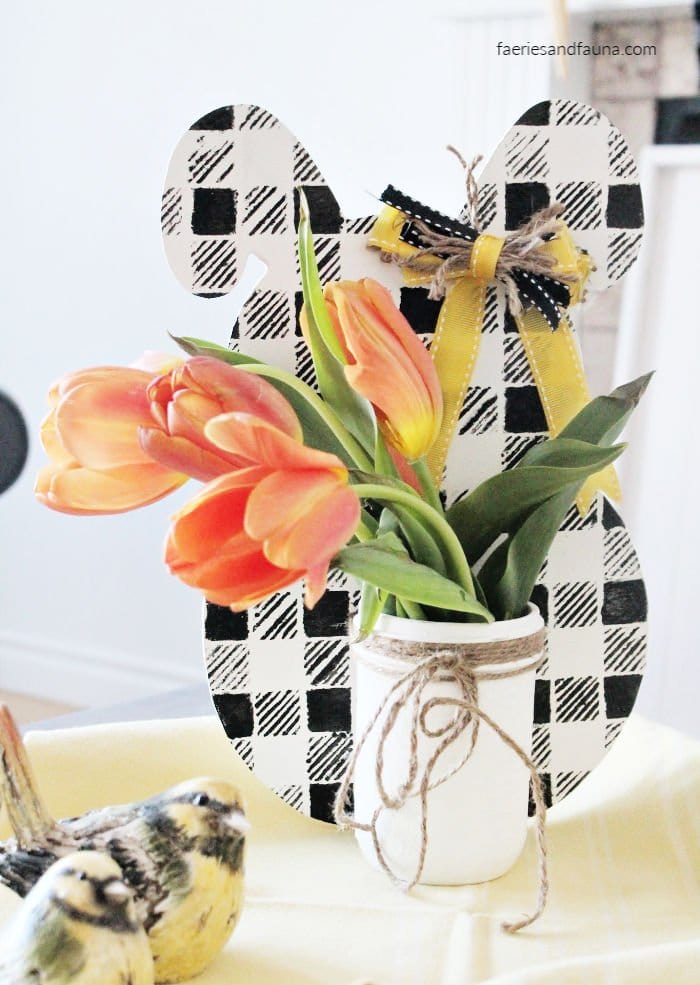 A DIY buffalo check Easter bunny vase with tulips.