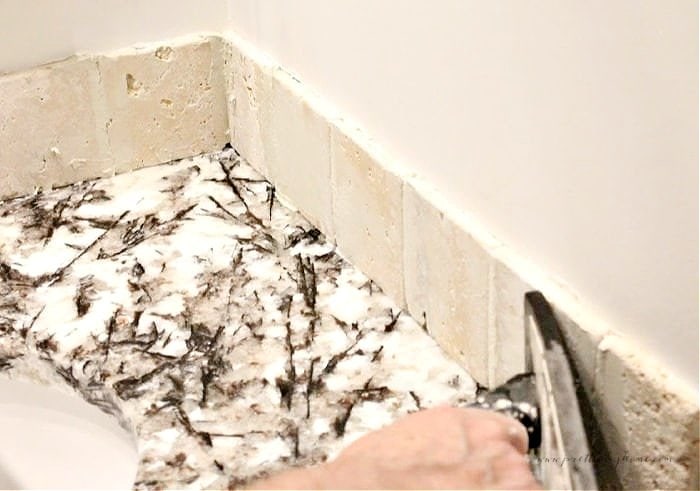 Smoothing the grout in a tile backsplash using a tile float trowel or sponge.