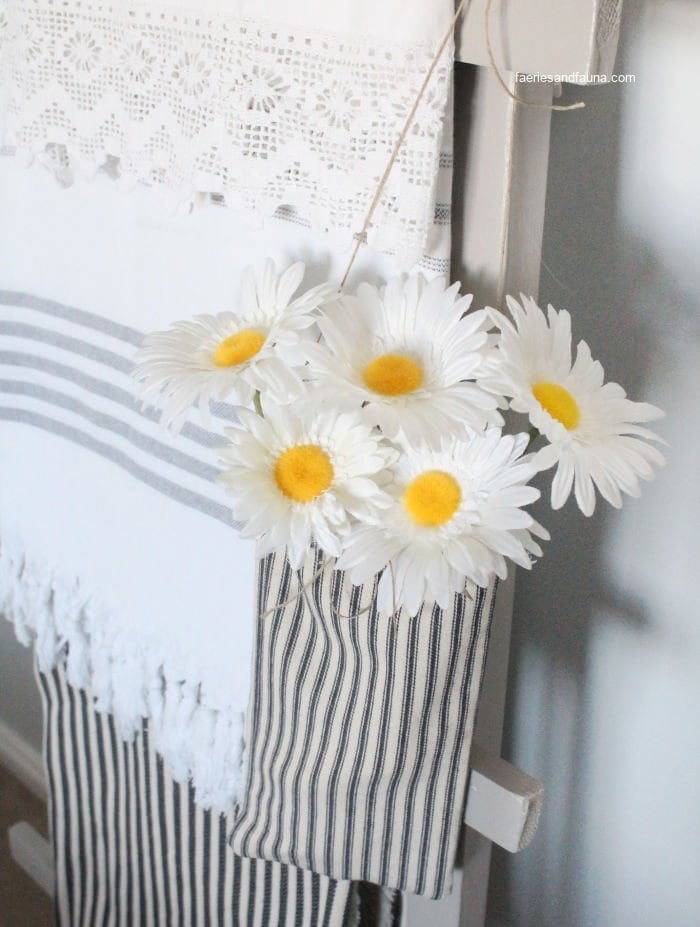 A small farmhouse pouch with flowers hanging on a ladder for farmhouse decor.