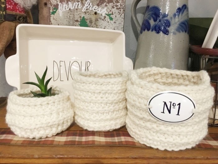 Three chunky homemade crochet baskets on a shelf in farmhouse style.