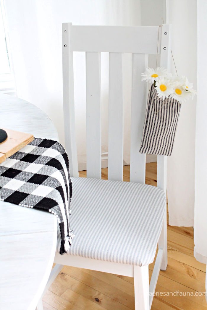 A chair refinished in white paint with a new sew farmhouse fabric seat cover.