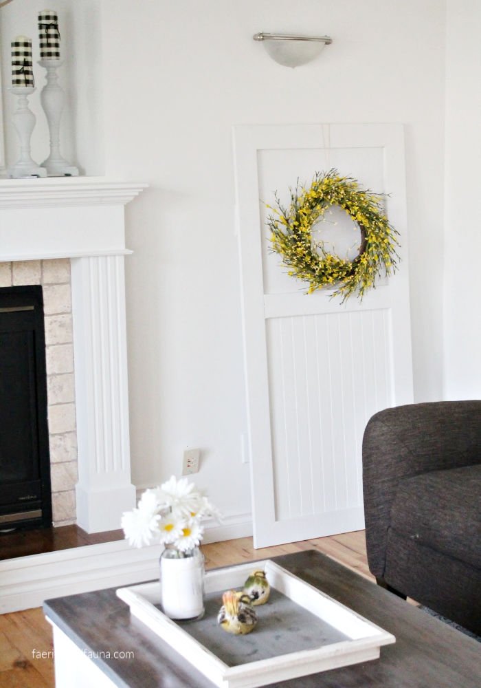 A DIY farmhouse door in white with shiplap for interior farmhouse decor. A pretty white backdrop with tongue and groove and a pretty wreath.