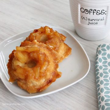 Almost like pineapple upside down cake. Two pineapple upside down cake donuts. The donuts on served on a plate with a large cup of coffee for an easy breakfast or sweet treat.