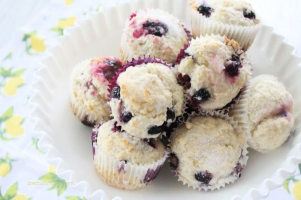 A stack of blueberry lemon muffins A bowl full of pretty blueberry lemon muffins in a white bowl. They have a light dusting of white sugar on top.