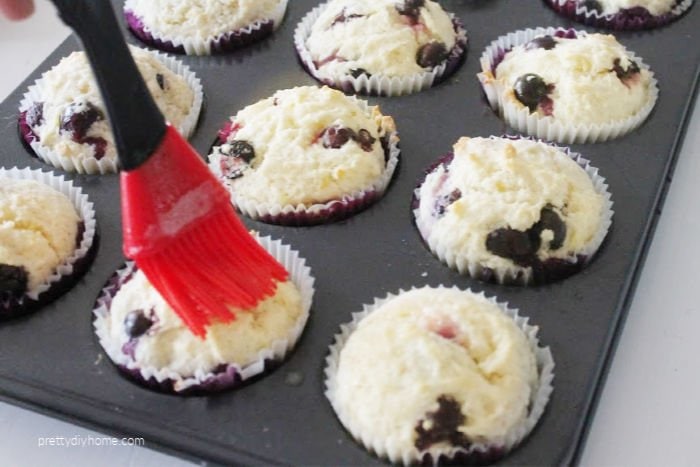 Basting fresh baked blueberry lemon muffins with lemon butter.