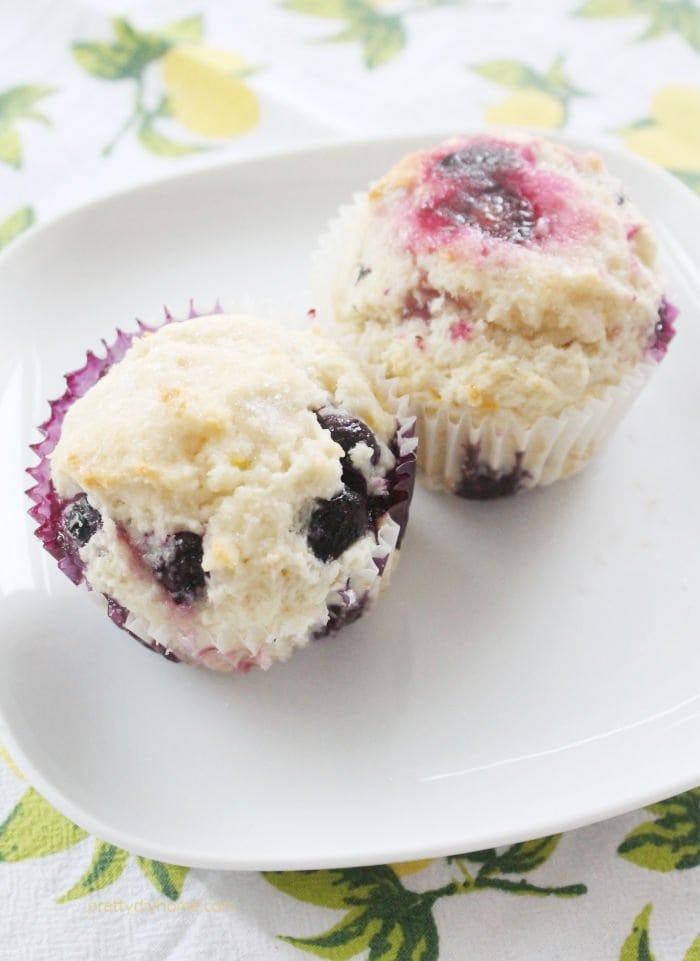 A plate with two delicious lemon blueberry muffins with a whtie streusel topping.