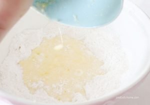 A large bowl full of dried lemon blueberry muffin ingredients, with a well in the middle for the wet lemon, egg and milk ingredients.