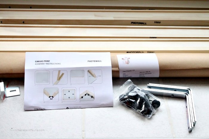 A box of supplies from Photowall for putting together a wall art canvas print. It includes printed instructions, frame, high quality canvas, and hardware.