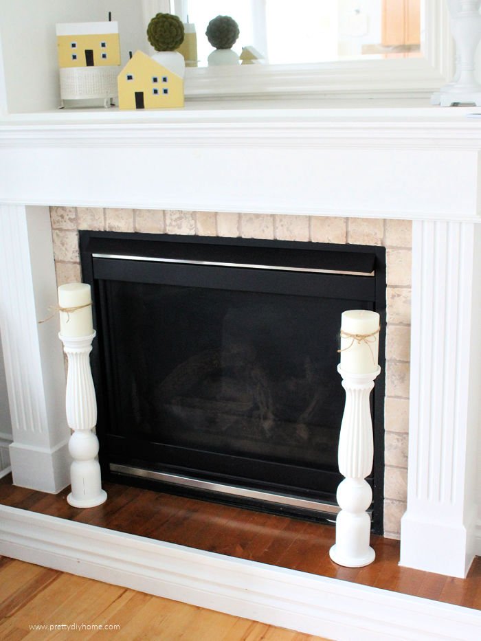 Two tall floor sized DIY candle holders flanking the front of a fireplace.