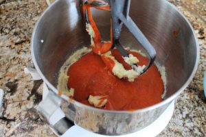 Adding tomato soup to tomato soup cake batter in a mixer