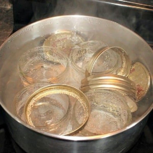 A large pot of boiling water full of canning jars for being sterilized in boiling water.