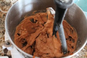 Mixing tomato soup cake batter with raisins, and walnuts in mixer bowl