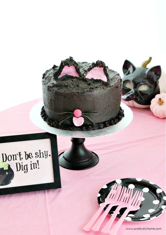 Easy Halloween Cake that looks like a black cat with pink ears and tongue.