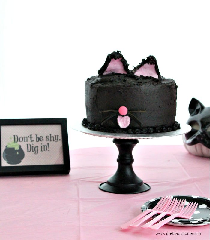 Simple and easy black cat cake with licorice whiskers and pink fondant ears. A not scary Halloween Party cake idea.