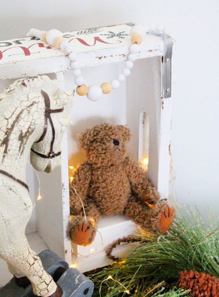 Handmade wooden Farmhouse Bead Garland for Christmas with a teddy bear, vintage boxes and a rocking horse.