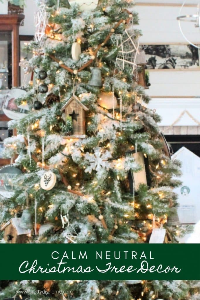 A large neutral farmhouse Christmas tree decorated with barn ornaments, galvanized bells, natural wood birdhouses and large Christmas ornaments.