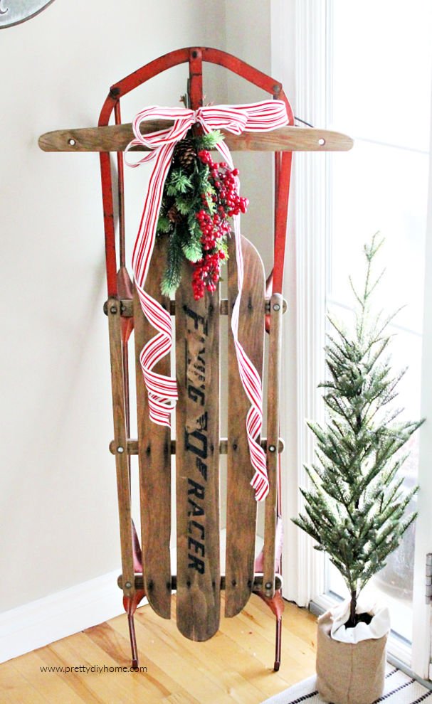 A large red sled and Christmas tree sitting in a Christmas entry way,