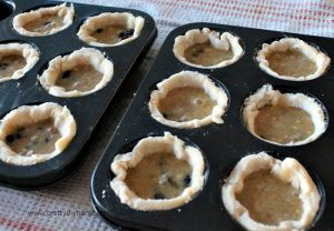 Filling tart tins with butter tart filling so that each tart is 2/3 full.