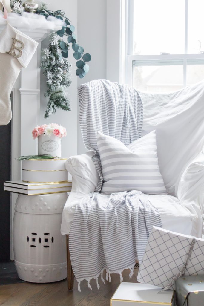 A white covered armchair with white throw, and white Christmas decor