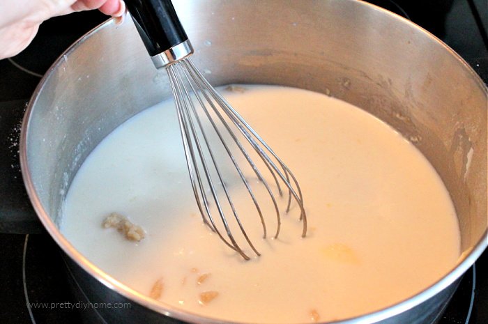 Butter, milk and flour in a saucepan with a whisk. Making the milk sauce for a classic scalloped potatoes recipe.