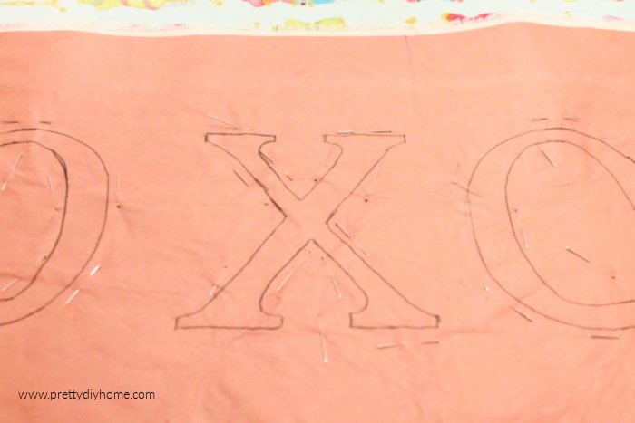 X and O letter on freezer paper with lots of sewing pins holding down all the letter edging.