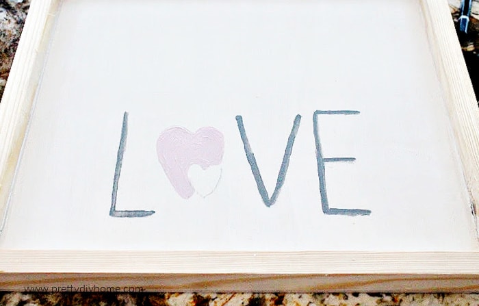 Hand painted word LOVE on a dollar store frame with natural sides and white background.  Done while making a Valentine wood sign craft.