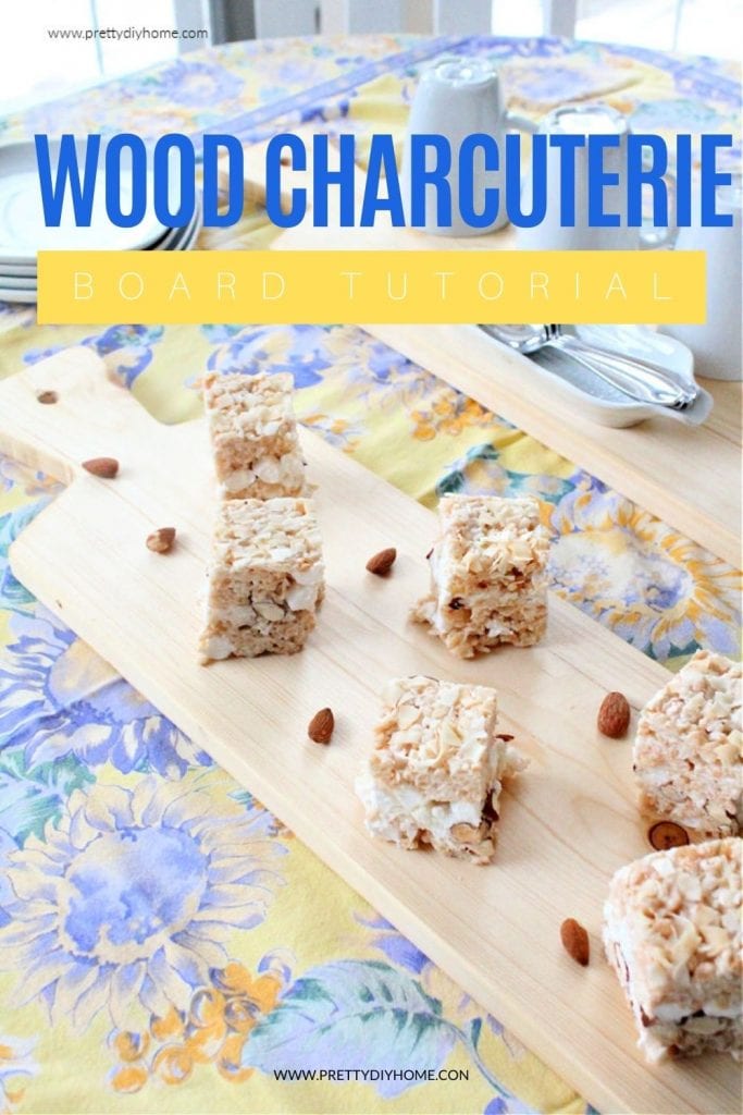 A handmade charcuterie board in light birch covered with rice krispie squares. There is a second matching serving board in the background holding coffee cups and spoons.
