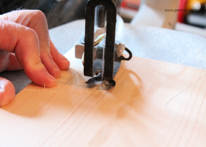 Using a scroll saw to cute out the handles on a wine bottle shaped Charcuterie Board.