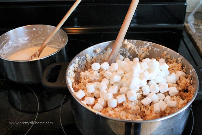 Mixing together coconut, rice krispies and marshmallows for a no bake square.