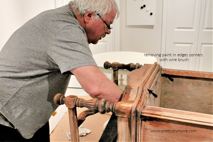 Using a small wire brush to remove little bits of chalk paint on a night stand makeover.