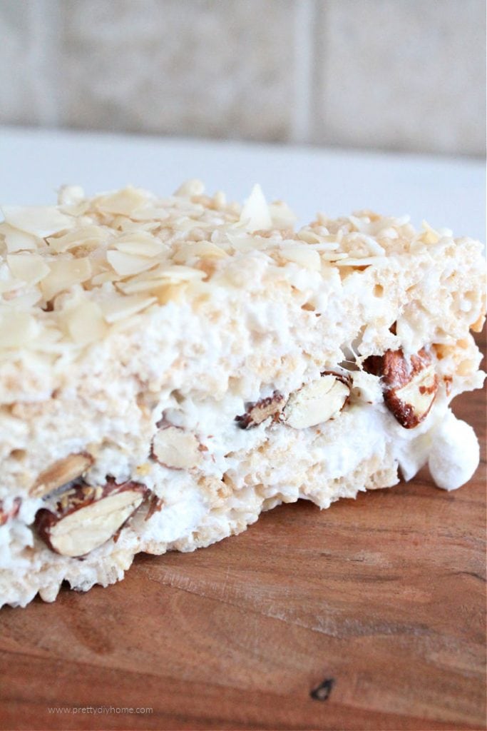 No bake squares with layers of rice krispies and a thick layer of marshmallow almonds and coconut in the middle