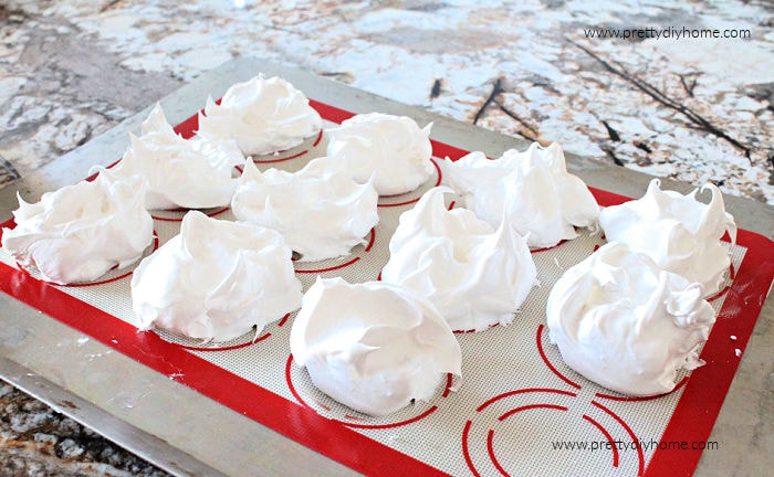 Three inch round mounts of light and airy pavlova batter on a silicone sheet before baking.