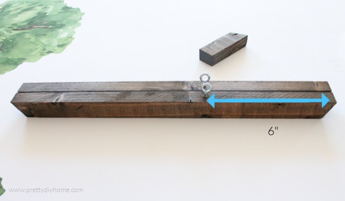 Placing screw eyes into a wooden poster frame, showing six inches from the end.