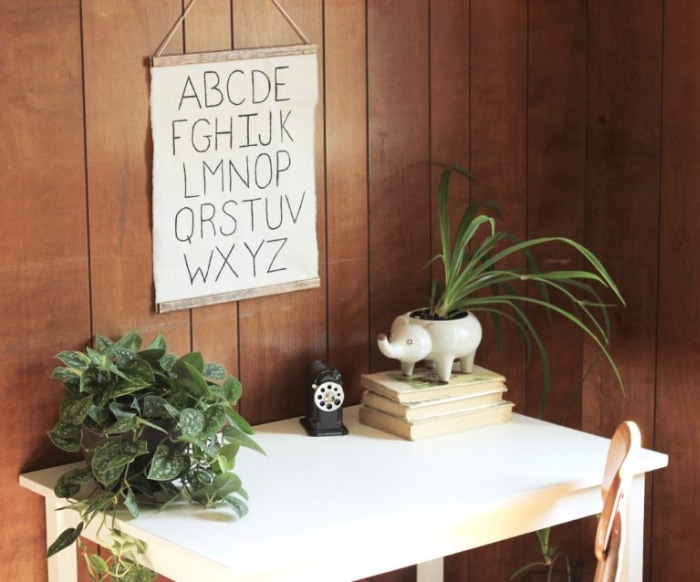 A handmade poster hanging over a desk that has plants a