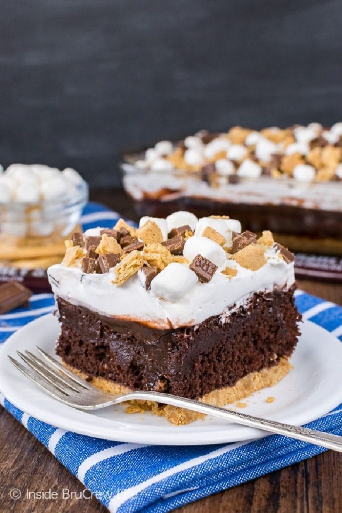 A large centered piece of chocolate Smores pudding cake with layers of graham crust, chocolate putddimg, melted marshmallows and crunchy bits of graham cookies, mini marshmallows and chocolate bits.