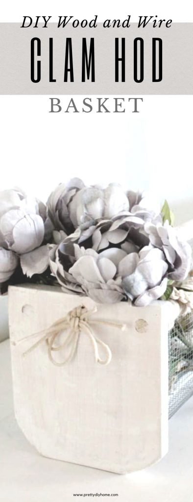 A diy clam hod basket painted white for fall decor. It has greyish flowers and white birch logs in it. They can also be used for eggs, or washing vegetables outdoors while gardening, but this one is indoors on a fireplace mantel for Fall decorating.