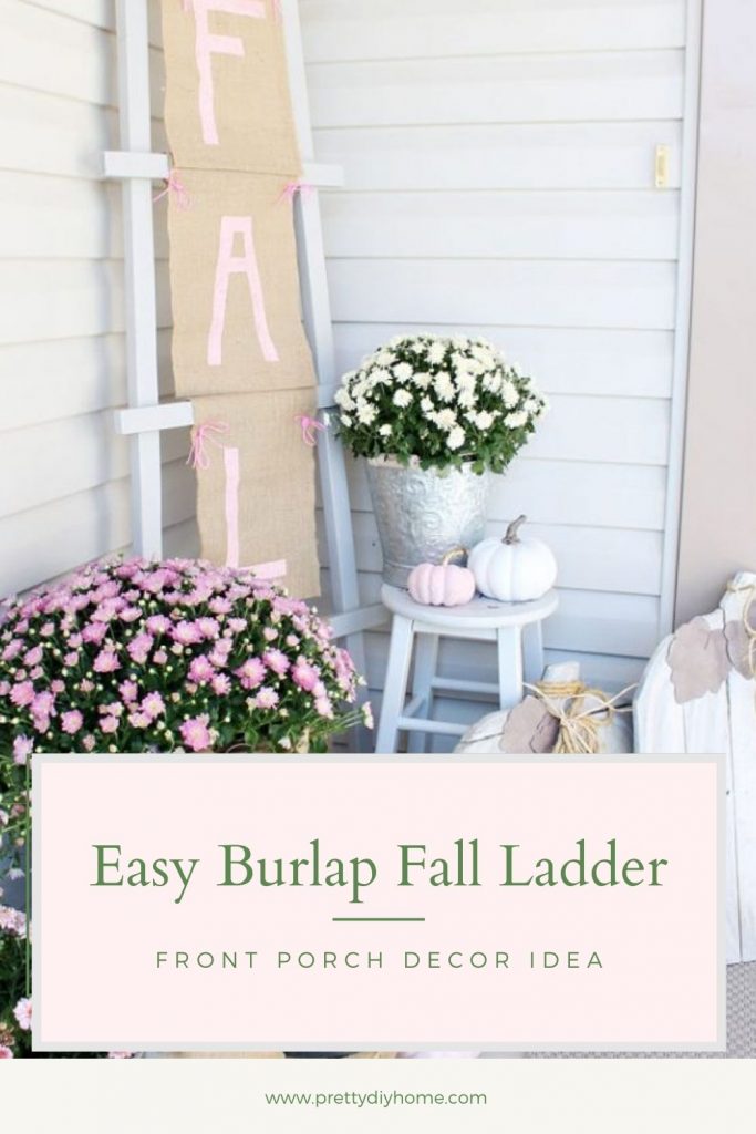 Fall front porch ideas in pinks and creams with pink mums with beautiful burlap bows, painted pink pumpkins and white wood stools. The background is a farmhouse ladder with a large Fall burlap banner with pink letters that say FALL.