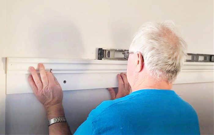 Attaching a shelf to the wall making sure it is level.