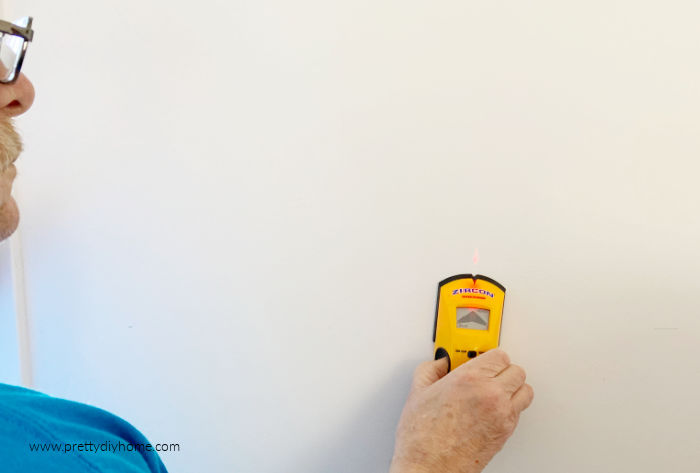 Using a stud finder for hanging pegboard shelves in the bedroom.