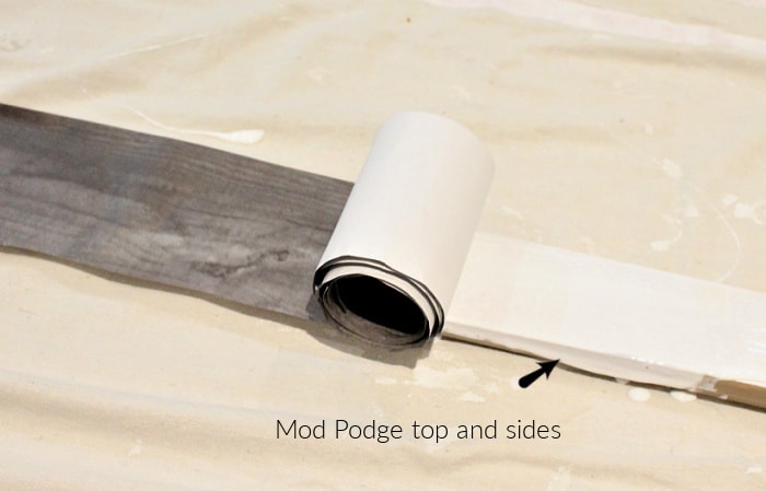 Rolling strips of wood grain paper onto skiis using mod podge.