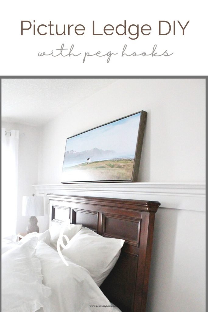 A master bedroom showing a wall length picture ledge with wooden peg hook for organization and decor. There is a large farmhouse beside the sea artwork leaning on the ledge.