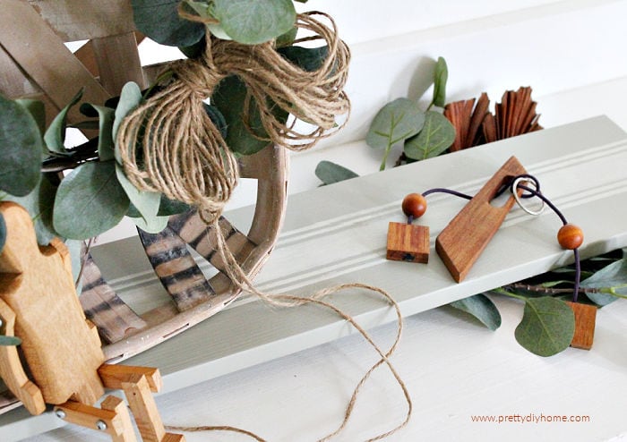 DIY table riser for farmhouse decor in soft green with ivory grain sack stripes. The table riser is displaying antique wood toys that were purchased at a garage sale.