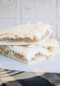 Two slices of homemade apple slab pie sitting on parchment paper. The apple pie has really light and flakey crust and a thin layer of fresh apple filling.
