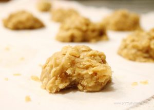 A tray of no bake peanut butter coconut cookies cooling on a tray. The front cookie is close up and you can see the chewy coconut fudgy layers inside the cookie.